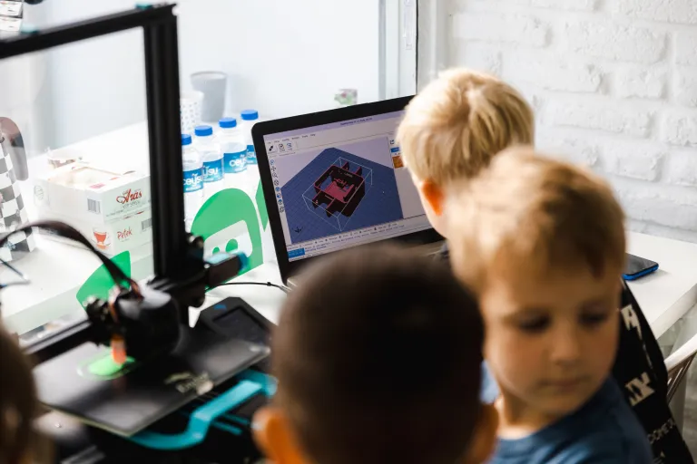 Drei Kinder modellieren am Laptop und drucken auf einem 3D-Drucker