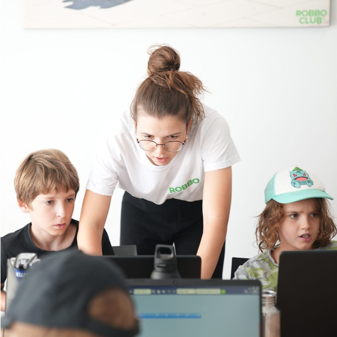 Eine Lehrerin unterstützt Kinder beim Arbeiten am Computer im Robbo-Camp.