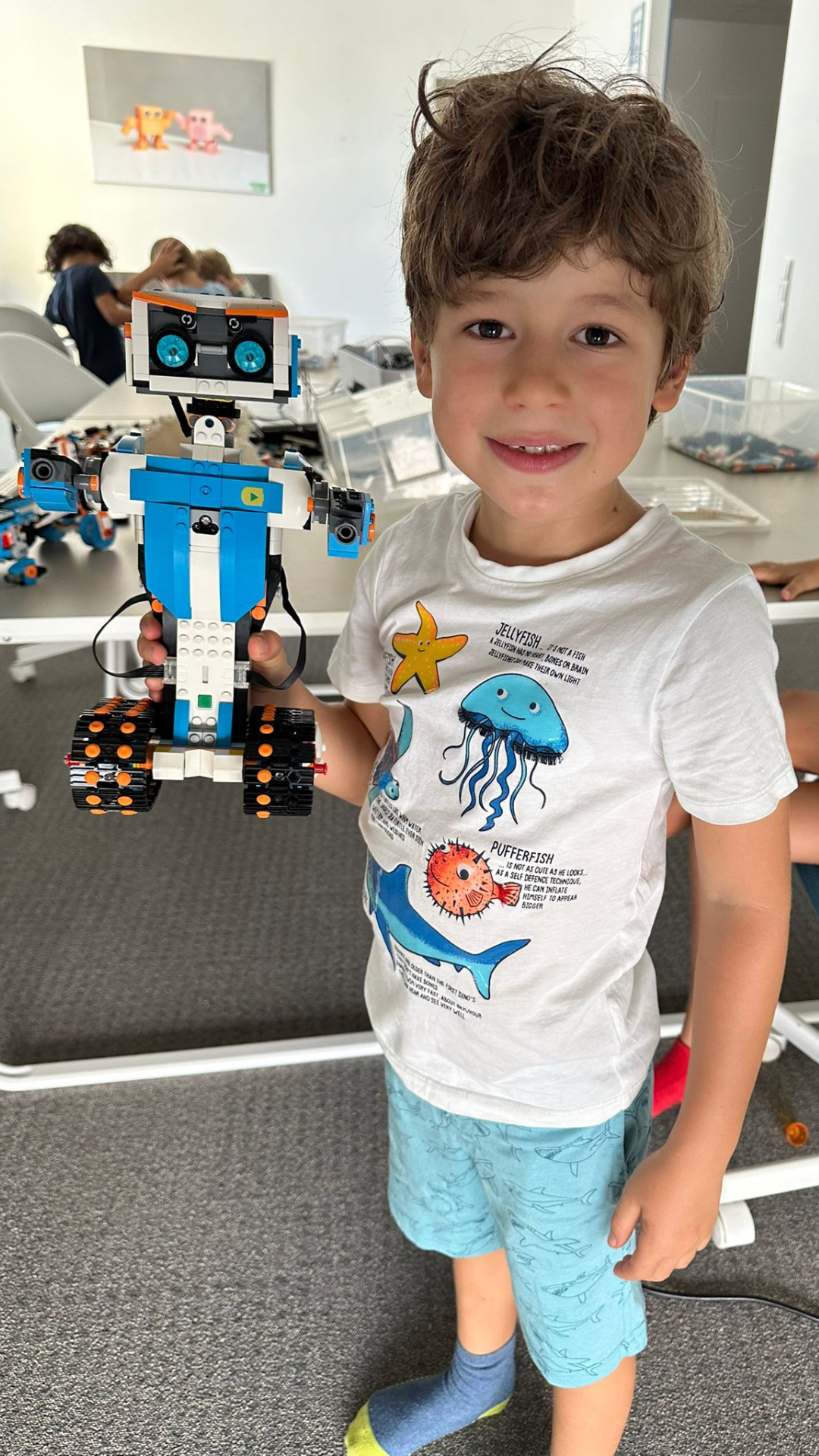 Ein Junge hält einen selbstgebauten LEGO-Roboter im Robbo Sommercamp.