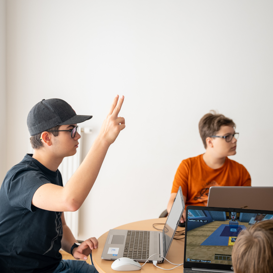 Jugendliche im Roblox-Sommercamp des Robbo Clubs programmieren eigene Spielewelten am Laptop.