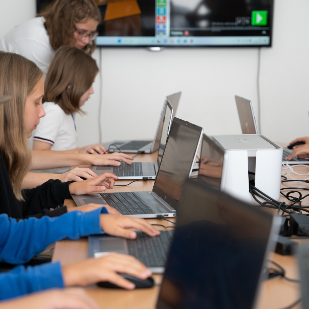 Kinder im Robbo Club Minecraft-Sommercamp arbeiten konzentriert an Laptops und gestalten eigene Welten.