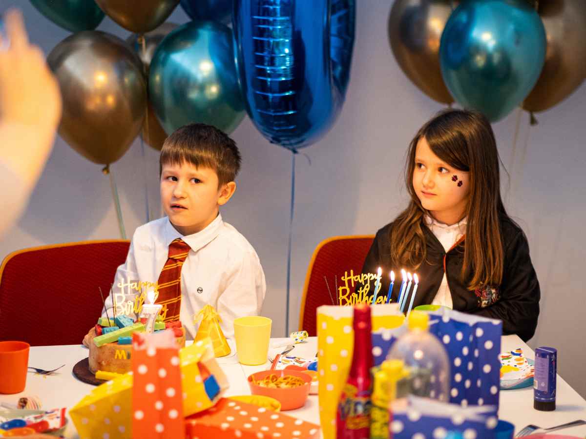 Kinder sitzen beim Geburtstagskuchen im ROBBO Club, umgeben von Luftballons und Deko.
