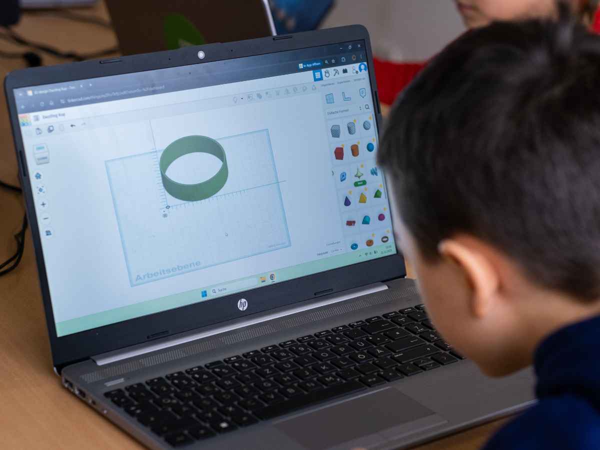 Kind arbeitet konzentriert an einem 3D-Modell auf dem Laptop.