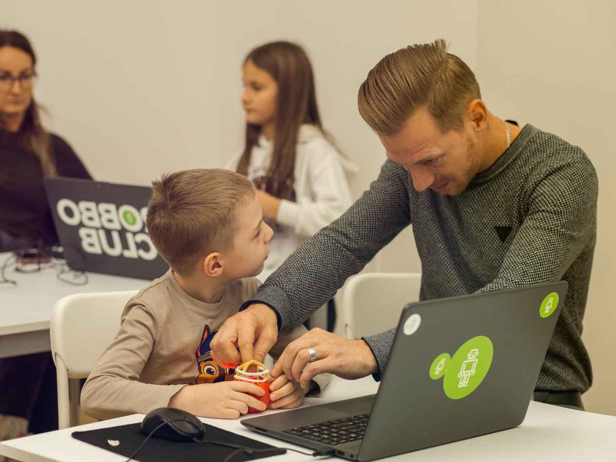 Trainer hilft einem Kind beim Bauen eines Technikmodells im Workshop.