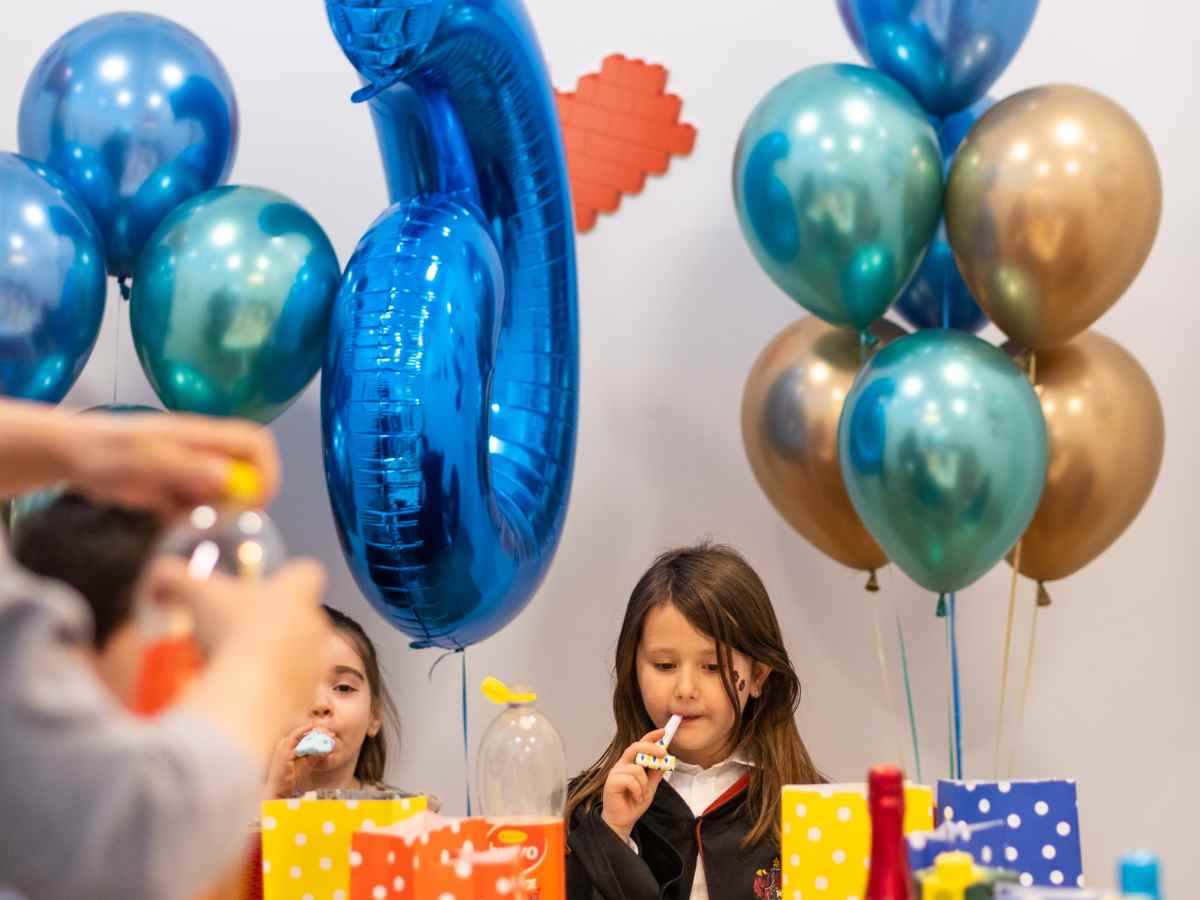 Kinder feiern einen Geburtstag am Tisch mit Ballons und Snacks im ROBBO Club.
