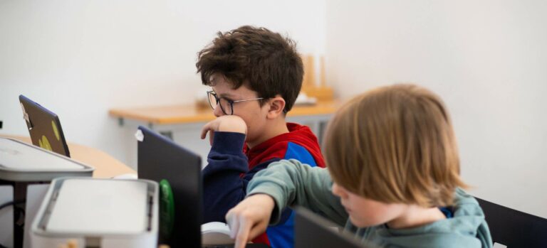 Zwei Kinder arbeiten konzentriert am Laptop während eines Roblox-Kindergeburtstags im Robbo Club