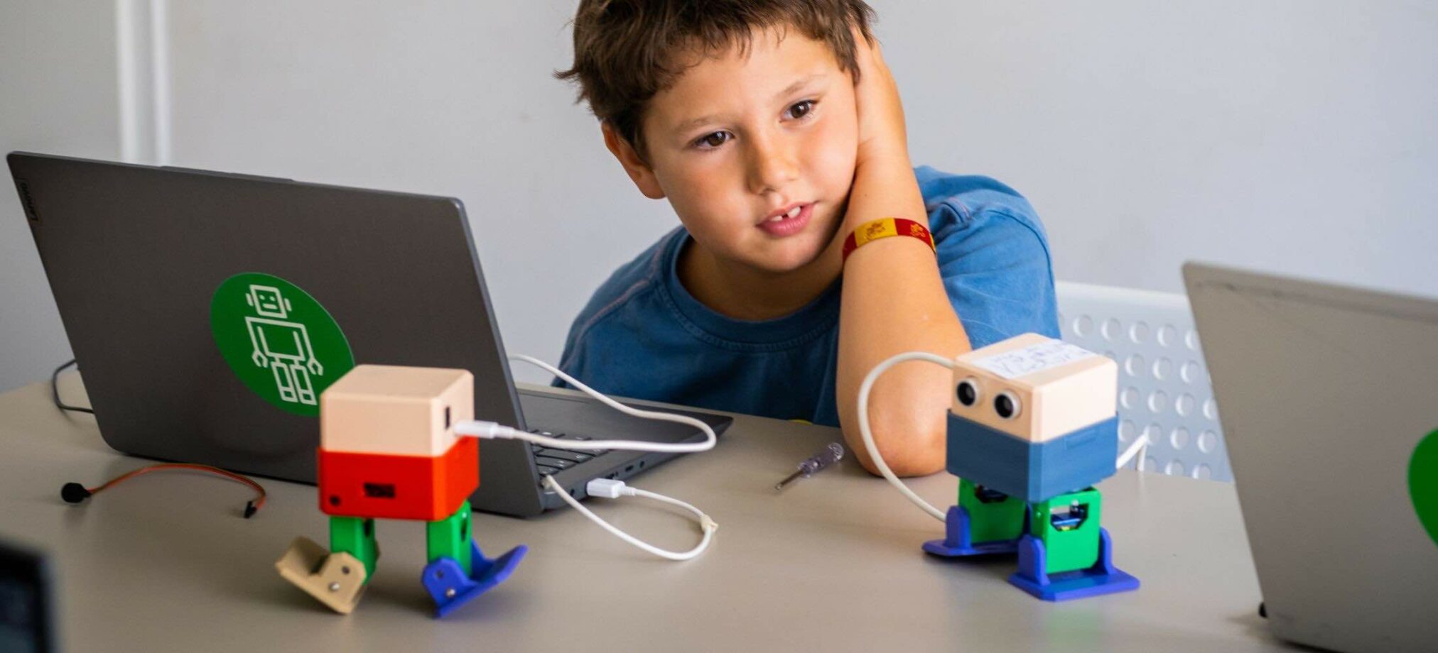 Ein Kind programmiert zwei kleine Roboter während eines Roboter-Kindergeburtstags im Robbo Club.