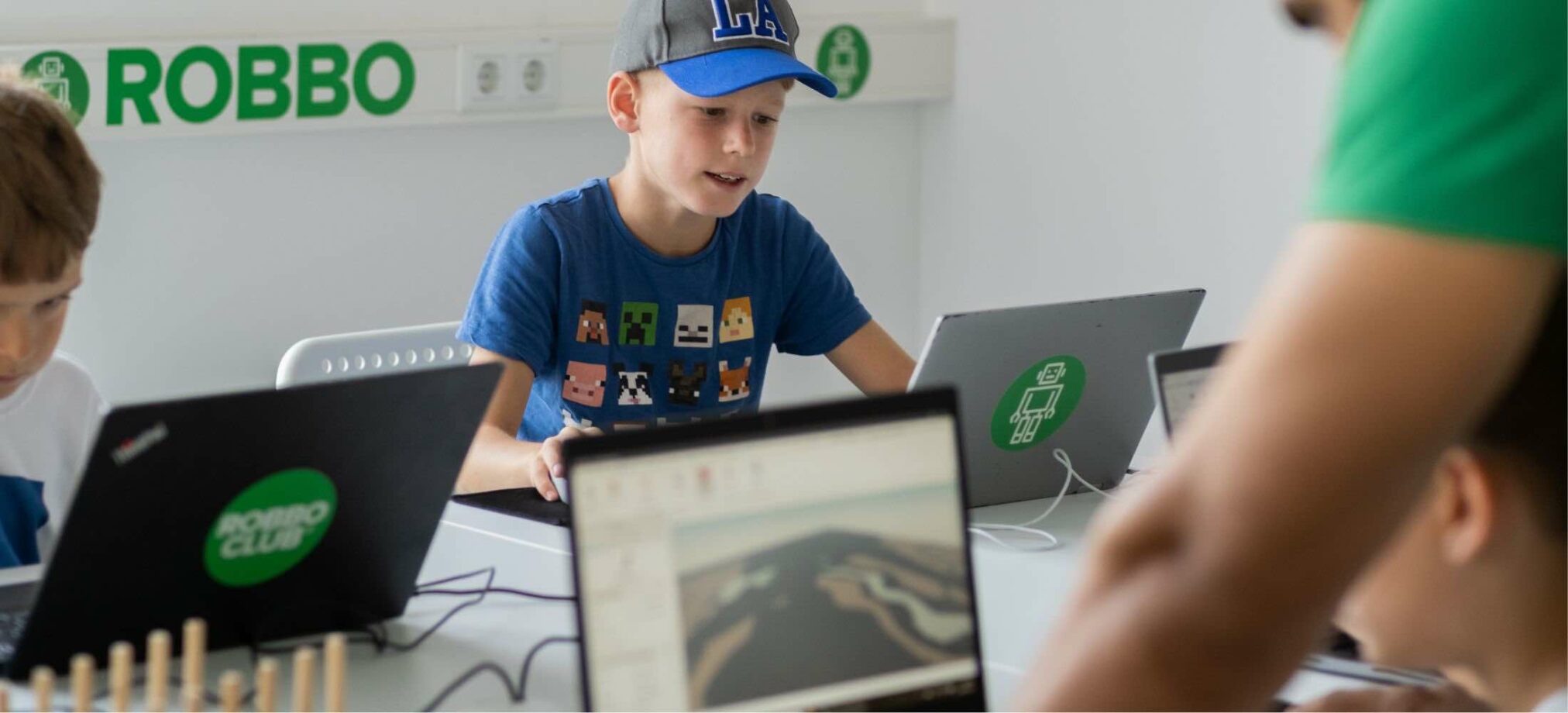 Kinder nehmen an einem Minecraft-Schnitzeljagd-Workshop im Robbo Club teil und arbeiten konzentriert an ihren Laptops.