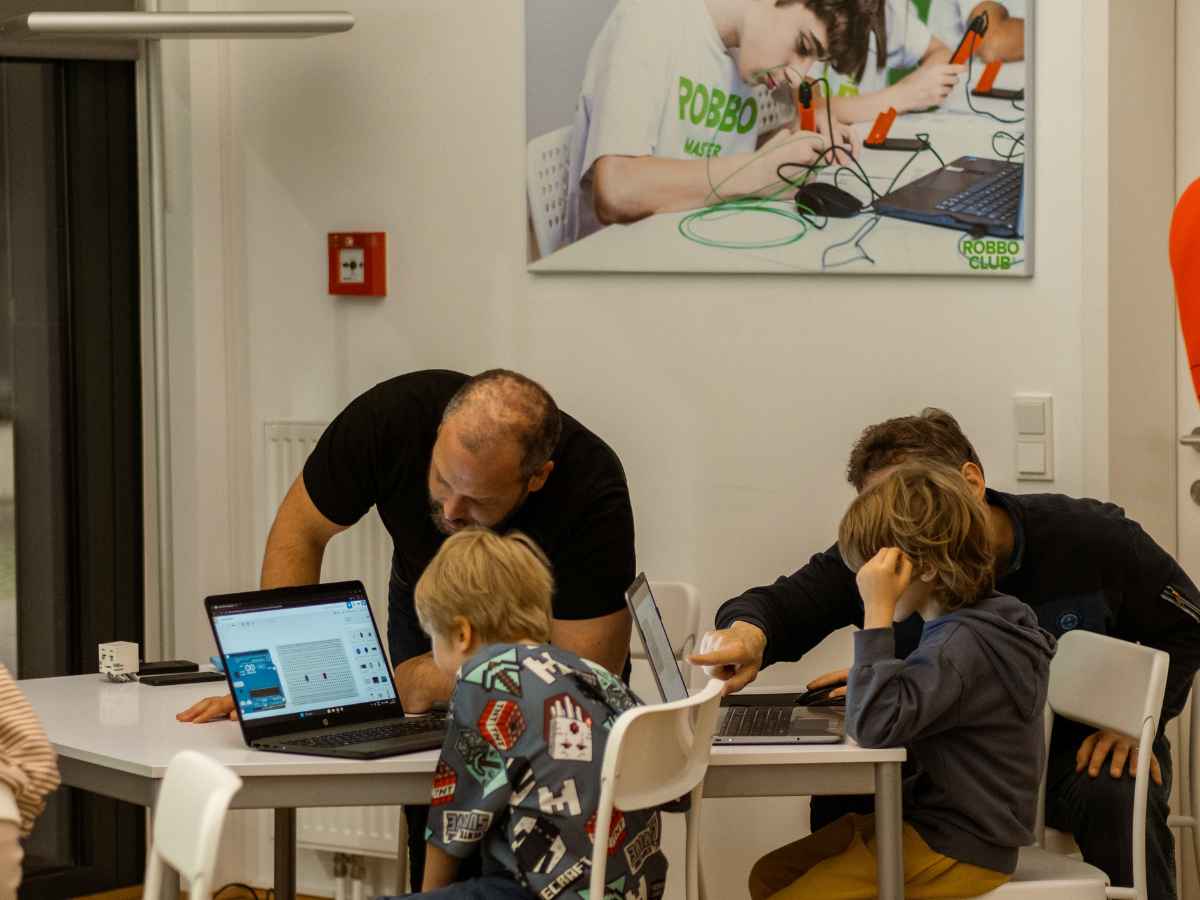 Kinder arbeiten im ROBBO Workshop an Laptops und Robotikprojekten.