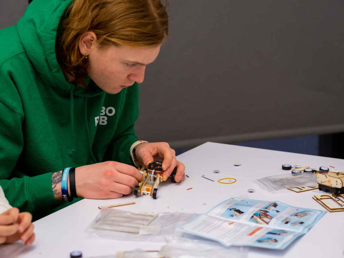 Jugendlicher baut ein mechanisches Modell im Workshop.