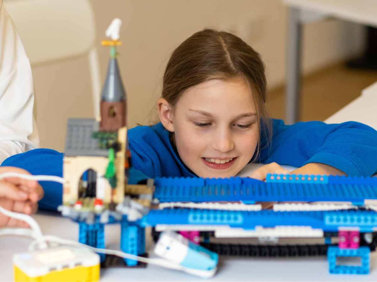 Mädchen baut im LEGO® Harry-Potter-Workshop des ROBBO Club Wien ein kreatives Modell.
