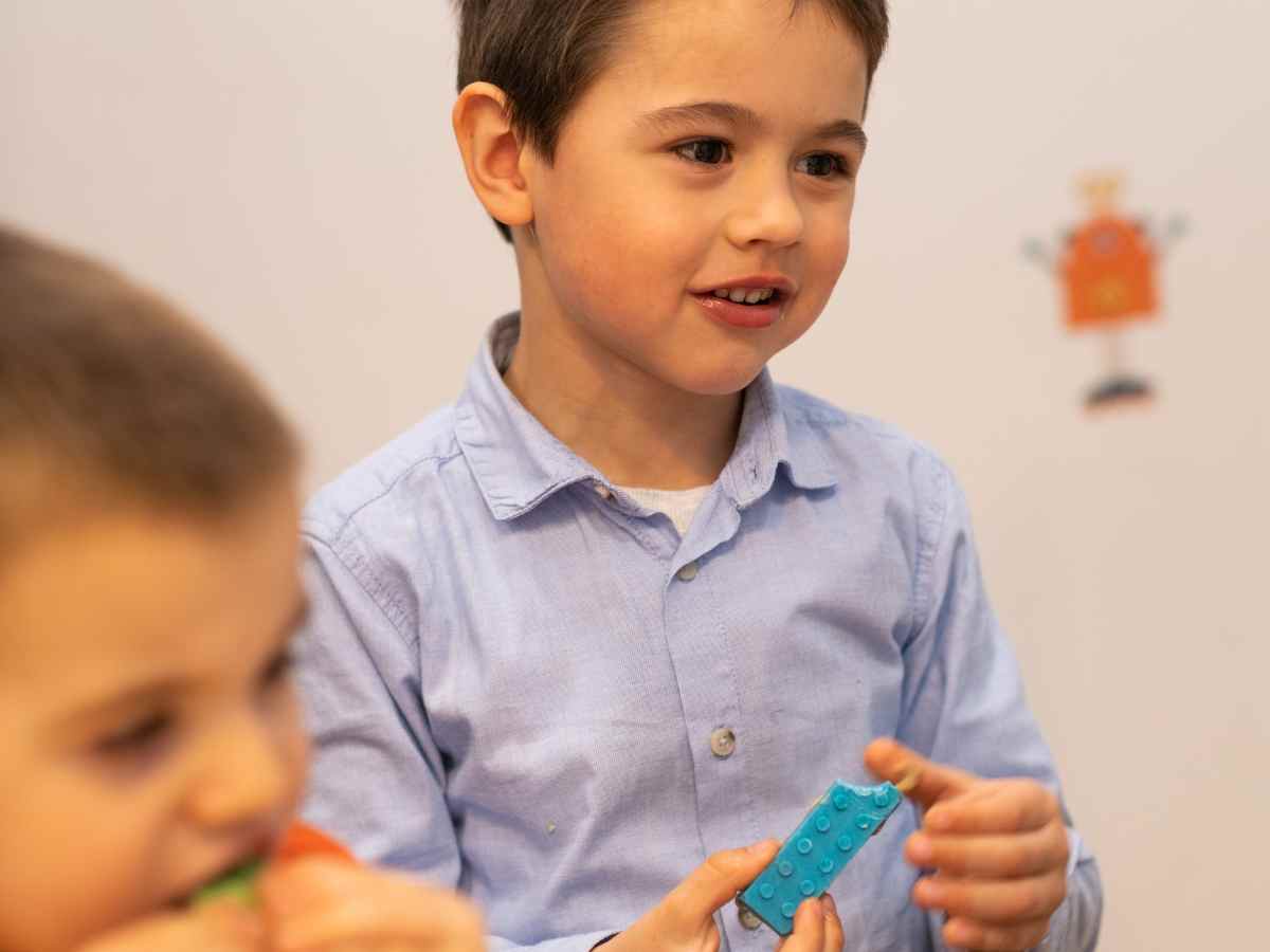 Kind hält ein LEGO Teil während des Workshops im ROBBO Club.