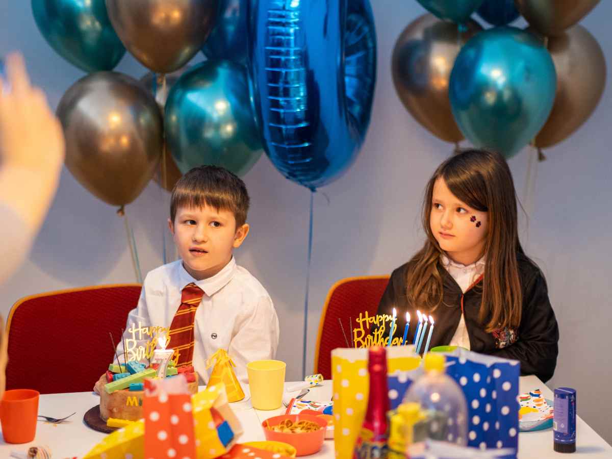 Kinder sitzen am Geburtstagstisch mit Kuchen und Dekoration im ROBBO Club.