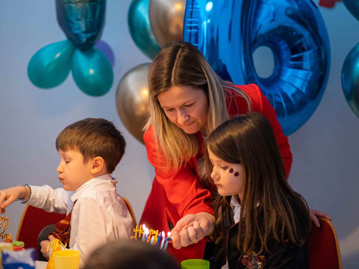Erwachsene hilft Kindern beim Anzünden der Geburtstagskerzen im ROBBO Club.