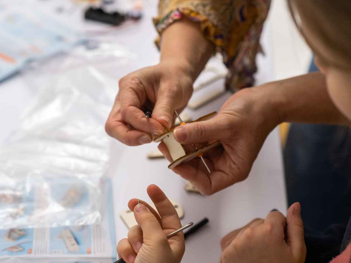 Erwachsene Hände helfen einem Kind beim technischen Bauen.