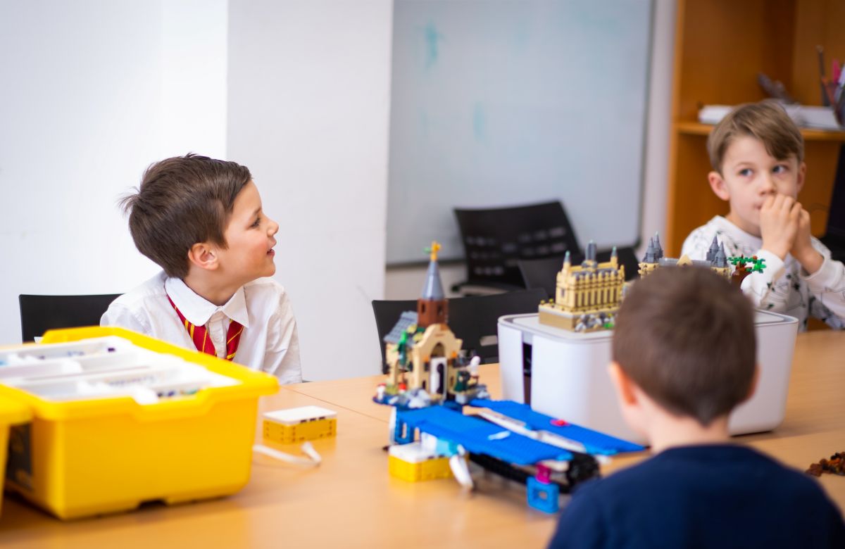 Konzentrierte Kinder beim Arbeiten mit LEGO und Laptops - Lernen durch praktisches Tun