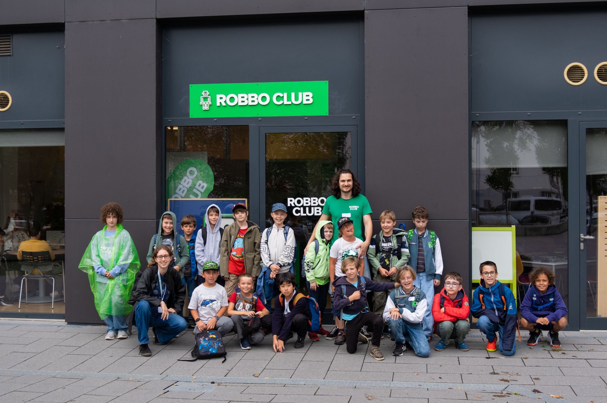 Kinder und Trainer im ROBBO Club Wien beim gemeinsamen Programmieren und Roboterbauen