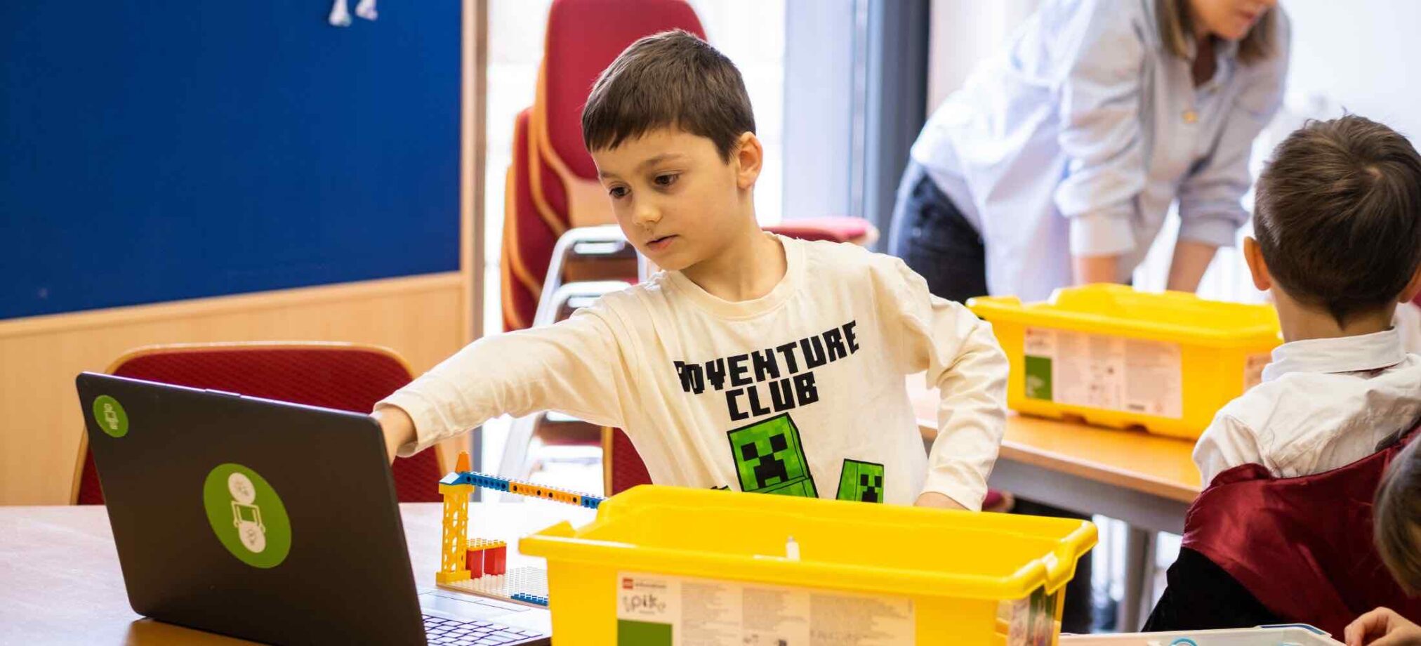 Ein Kind im Robbo Club steuert am Laptop ein LEGO-Projekt während eines 10. Geburtstags kreativ und konzentriert.