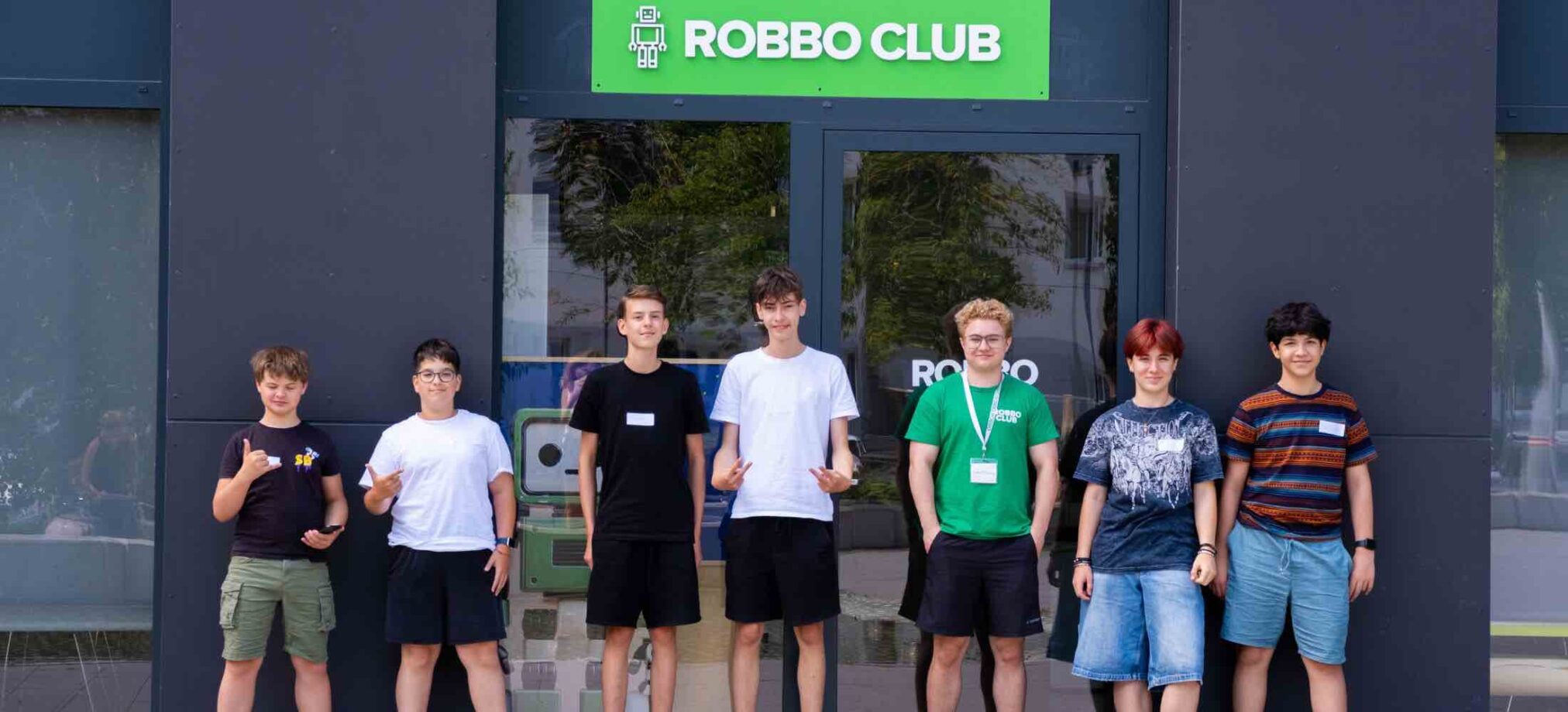 Jugendliche ab 12 Jahren stehen vor dem Robbo Club Gebäude und nehmen am Feriencamp teil.