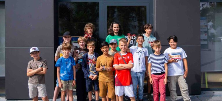 Kindergruppe beim Robbo Club Sommercamp für Drohnenbau und Programmierung, gemeinsam mit ihren Trainern vor dem Clubgebäude.