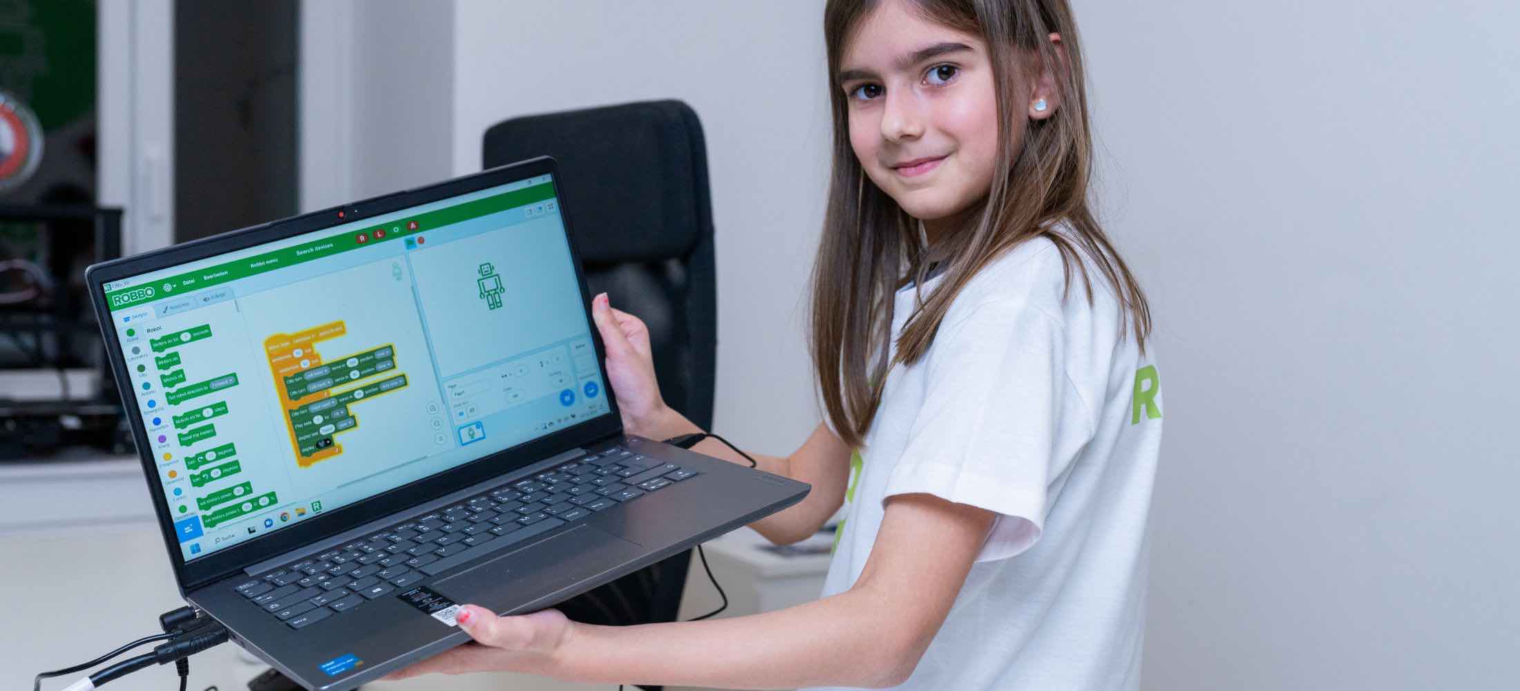 Ein Kind zeigt am Laptop ein selbst erstelltes Scratch-Programm mit farbigen Codeblöcken im Robbo Club.
