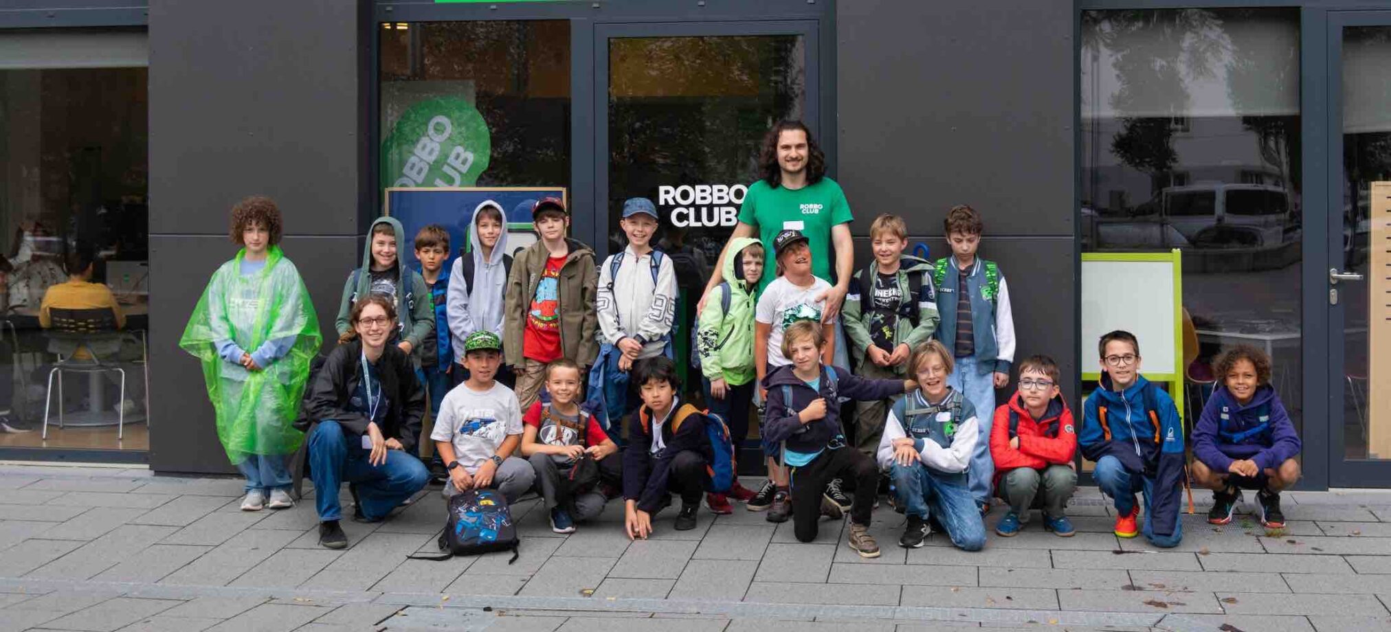 Kinder und Betreuer des Robbo Club Herbstcamps stehen gemeinsam vor dem Clubgebäude für ein Gruppenfoto.