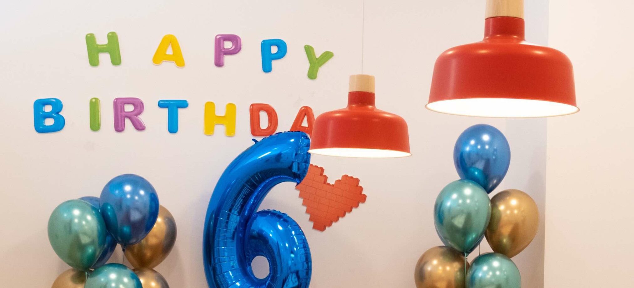 Dekorierter Partyraum im Robbo Club mit bunten „Happy Birthday“-Buchstaben, Ballons und einer großen blauen Zahl 6.