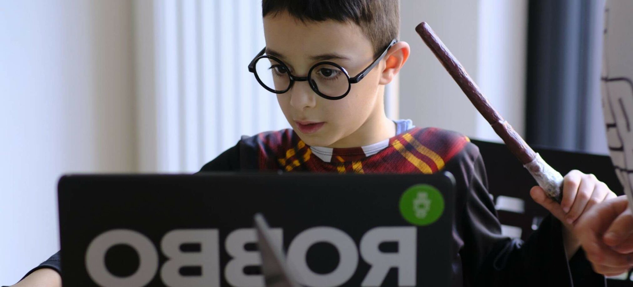 Ein Kind im Zauberer-Kostüm arbeitet konzentriert am Laptop beim Robbo Club Kindergeburtstag.