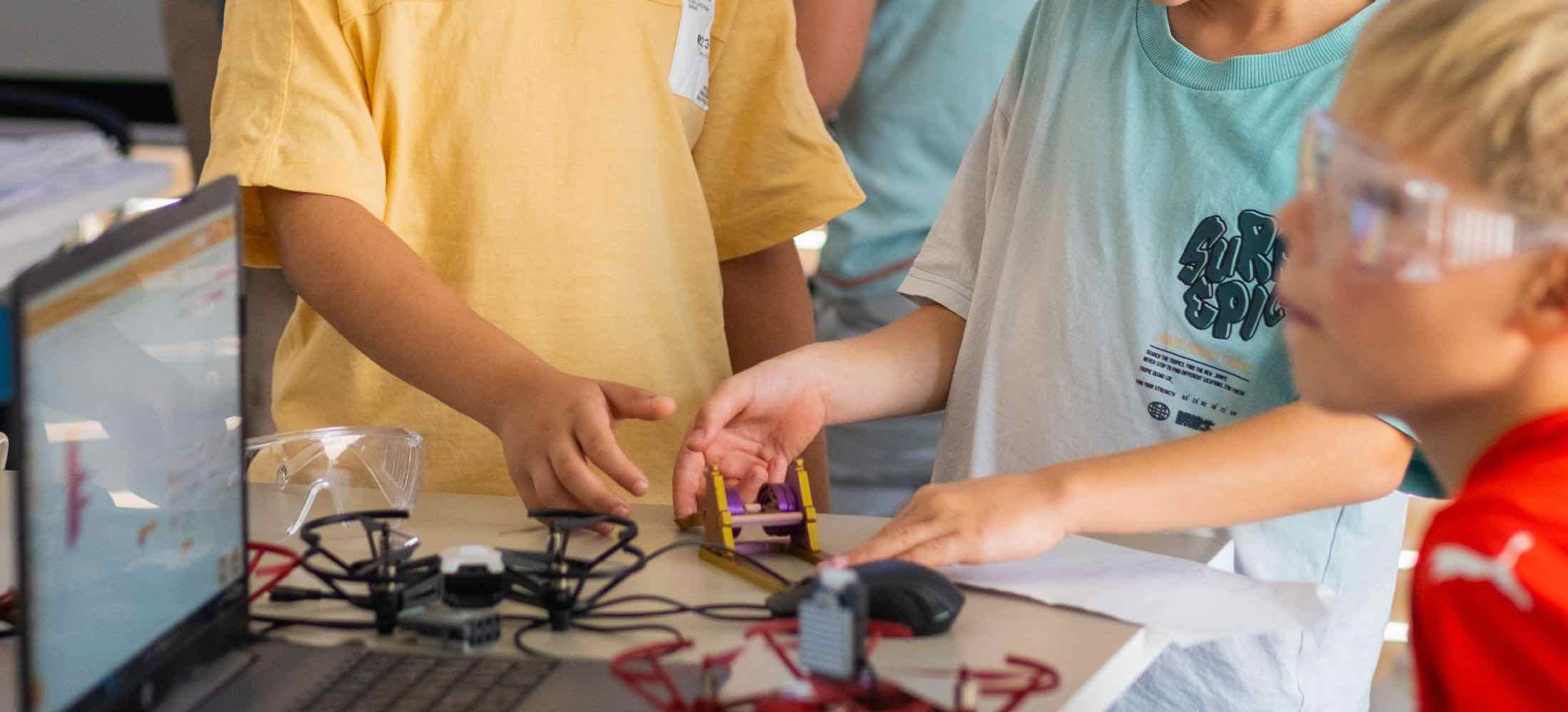 Kinder im Robbo Club Kurs arbeiten gemeinsam an einem Drohnenprojekt und mechanischen Modellen.