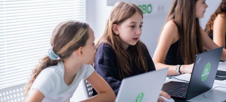 Zwei Mädchen im Robbo Club arbeiten konzentriert an ihren Laptops im Programmierkurs.