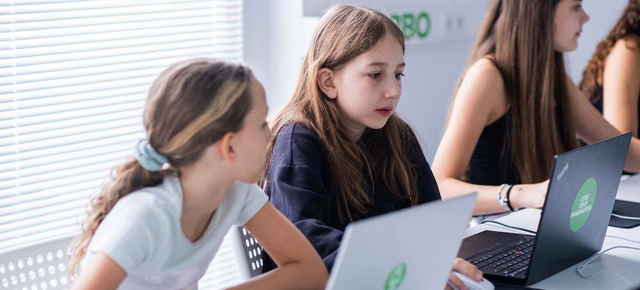Zwei Mädchen im Robbo Club arbeiten konzentriert an ihren Laptops im Programmierkurs.