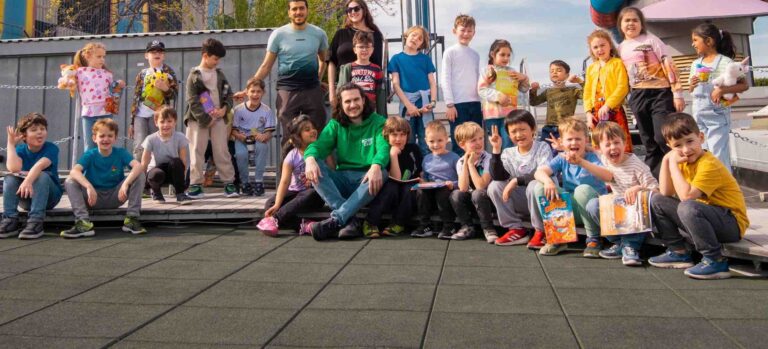 Kinder und Betreuer des Robbo Club Feriencamps genießen gemeinsame Aktivitäten während der Osterferien und posieren für ein fröhliches Gruppenfoto im Freien.