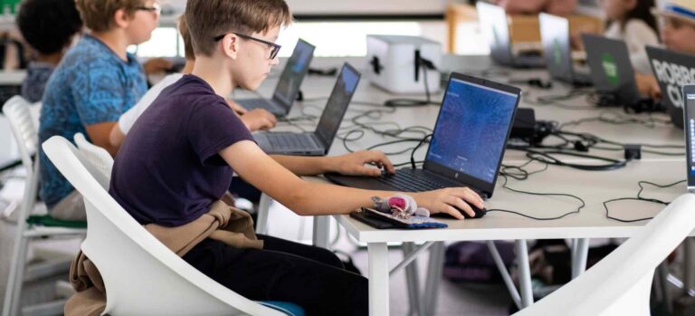 Ein Jugendlicher arbeitet konzentriert am Laptop im Robbo Club und programmiert einen Roboter im Rahmen eines Kurses für 11- bis 15-Jährige.