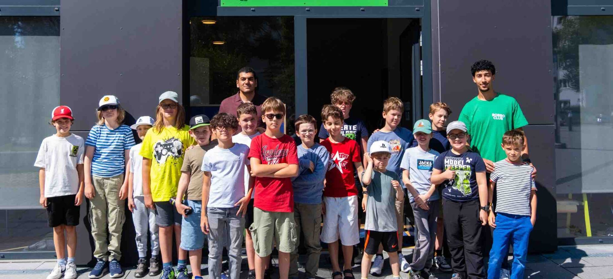 Kinder ab 9 Jahren stehen mit ihren Betreuern vor dem Robbo Club Gebäude während des Feriencamps.