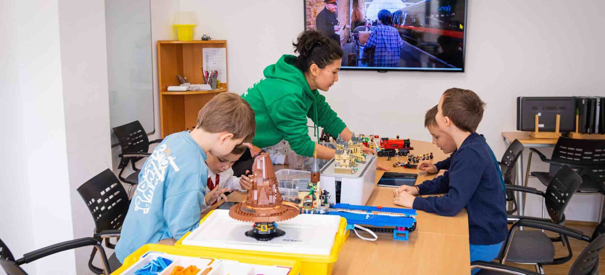 Kinder im Harry-Potter-Feriencamp des Robbo Club bauen mit LEGO magische Szenen nach und arbeiten gemeinsam an kreativen Projekten.