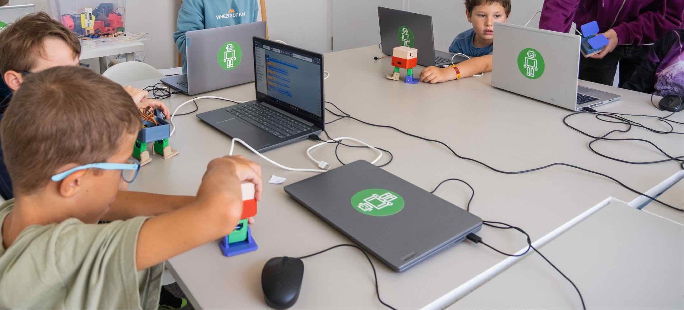 Kinder zwischen 8 und 10 Jahren programmieren im Robbo Club kleine Roboterfiguren und testen ihre Funktionen am Laptop.