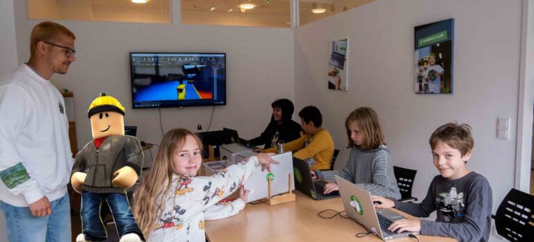 Kinder sitzen im Roblox-Workshop des Robbo Clubs am Laptop und entwickeln eigene Spielewelten.