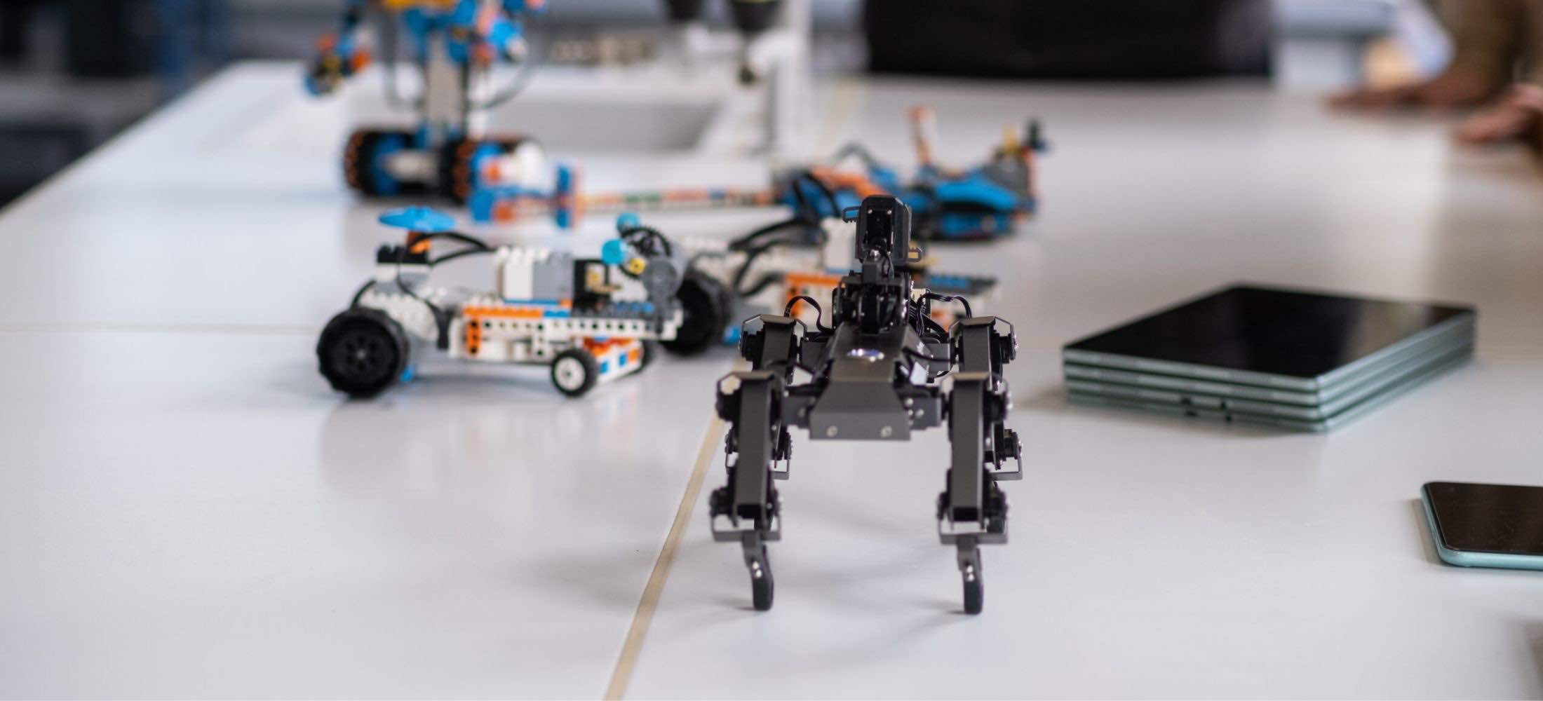Mehrere verschiedene Roboter stehen auf einem Tisch im Robbo Club und werden für Robotik-Workshops vorbereitet.