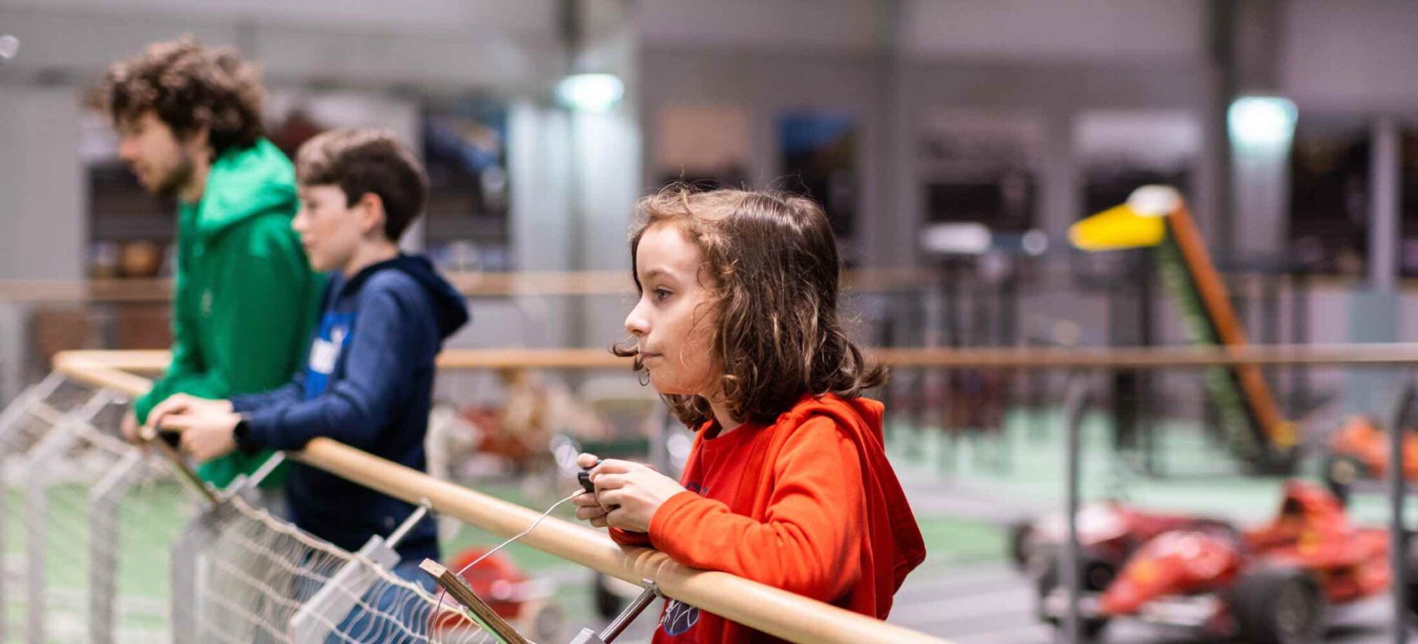 Kinder und Betreuer des Robbo Clubs beobachten eine technische Ausstellung und steuern Modelle während des Semesterferiencamps.