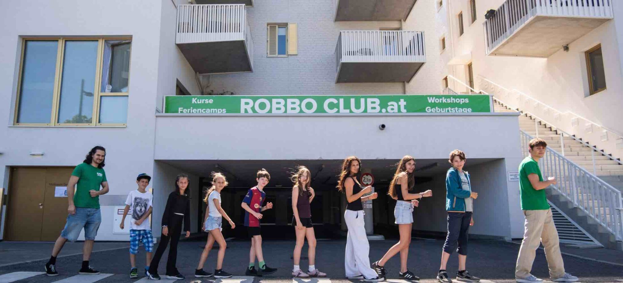 Kinder und Jugendliche stehen vor dem Robbo Club Wien und posieren gemeinsam für ein Foto im Rahmen der Sommerkurse.