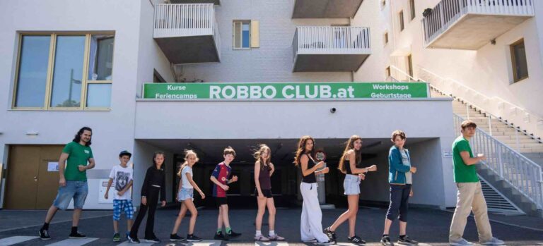 Kinder und Jugendliche stehen vor dem Robbo Club Wien und posieren gemeinsam für ein Foto im Rahmen der Sommerkurse.