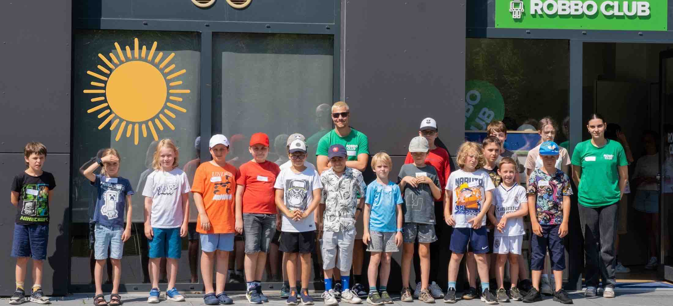 Eine Gruppe von Kindern steht gemeinsam mit Robbo-Club-Trainerinnen und Trainern vor dem Clubgebäude und nimmt an einem Tag-der-Sonne-Workshop teil.