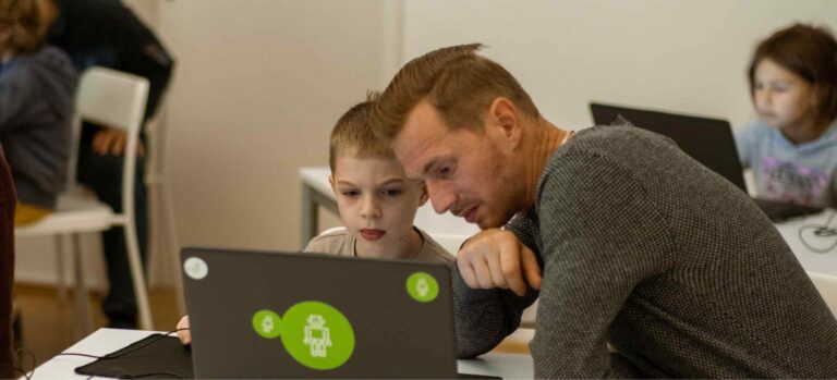 Ein Vater und sein Kind arbeiten gemeinsam am Laptop während eines Vatertags-Workshops im Robbo Club.