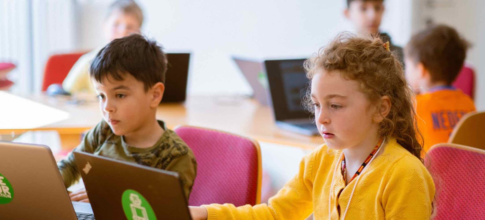 Kinder arbeiten konzentriert an Laptops im Robbo Club Wintercamp und lernen spielerisch zu programmieren.