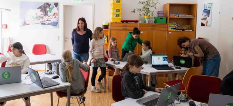 Kinder arbeiten im Robbo Club an Technik- und Kreativprojekten, während Trainerinnen und Mütter unterstützend dabei sind – im Rahmen eines Muttertags-Workshops.