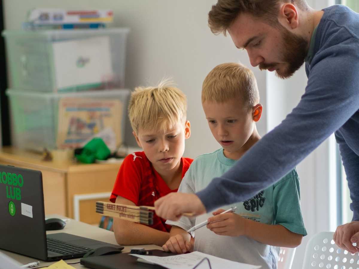Kind arbeitet konzentriert am Laptop mit Roboterfigur