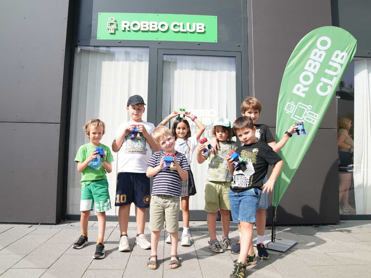 Kinder präsentieren ihre Roboterprojekte vor dem Robbo Club Eingang