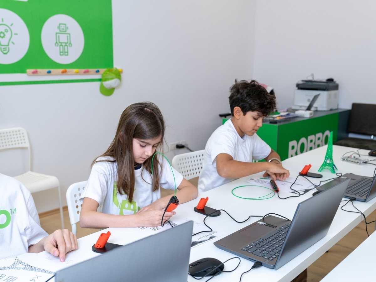 Kinder arbeiten mit Laptops und Elektroniksets im Unterricht