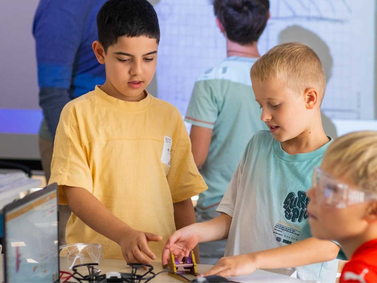 Kinder bauen gemeinsam ein technisches Modell und diskutieren die Konstruktion.