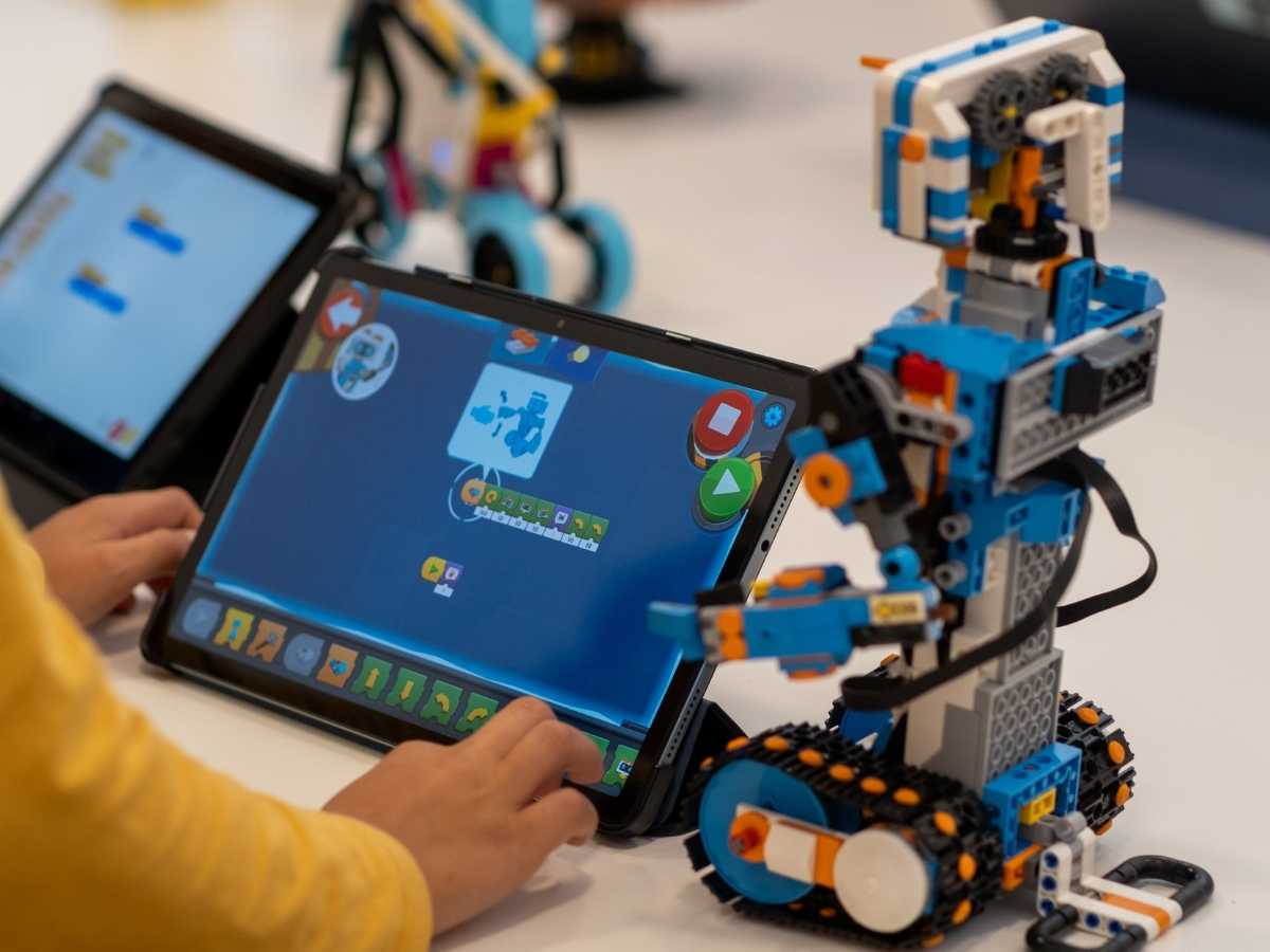 Kind programmiert einen Roboter mit einem Tablet